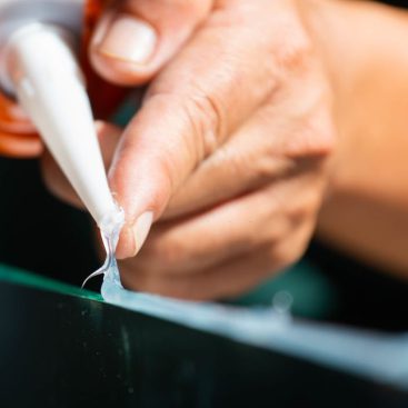 Men's hand uses silicone adhesive with adhesive to connect the mirror with aluminum.